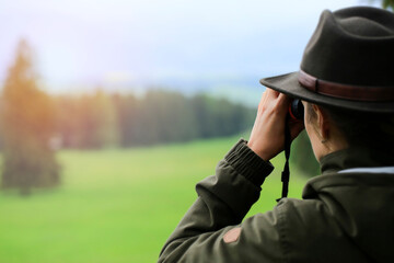  Hunter woman with  binoculars  looking  wild animals in the green country. copy space for text.