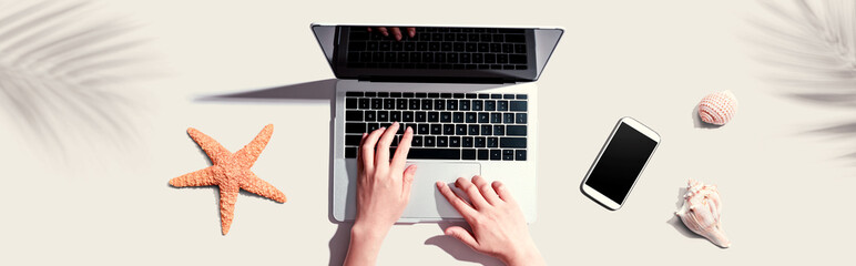 Poster - Person using a laptop computer with shells and starfish - flat lay