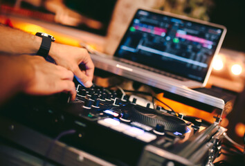 Overhead shot of Dj controling red party dj audio equipment.Turntable top view High quality mixing controller disc jockey in night club and notebook .Pro audio equipment on stage in nightclub.