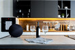 luxury studio apartment with a free layout in a loft style in dark colors. Stylish modern kitchen area with an island, cozy bedroom area with fireplace and personal gym