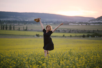 Young beautiful woman relaxing in summer field of yellow flowers.