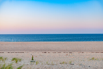 Wall Mural - Wide beach and sea background under pink and blue sunset sky.