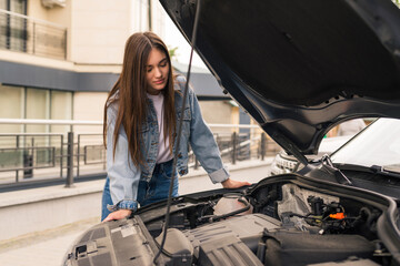 Young woman waits for assistance near her car broken down on the road side.