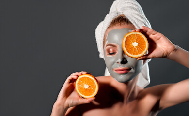 Beautiful woman with clay mask on a gray background.