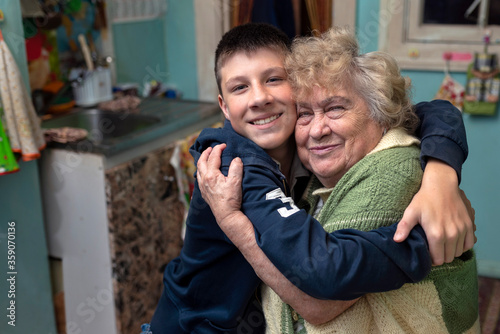 Fotomural Happy, smiling grandson hugs his grandmother in the kitchen at home