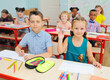 © Evgeniy Kalinovskiy - a group of school children are smiling at a Desk with colored pencils and sketchbooks in a drawing lesson in a primary or elementary school against the backdrop of a modern classroom. Back to school,