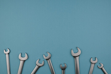 Set chrome spanner keys lying side by side on blue background. Flat lay, top view, minimal composition with copy space