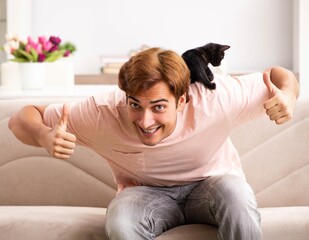 Young man playing with kitten at home