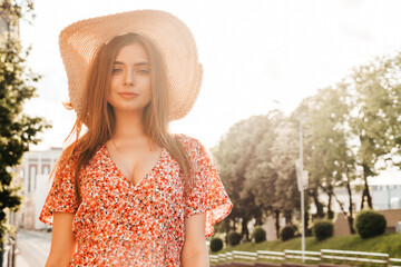 Portrait of young beautiful hipster girl in trendy summer sundress.Sexy carefree woman posing on street background in hat at sunset. Positive model outdoors