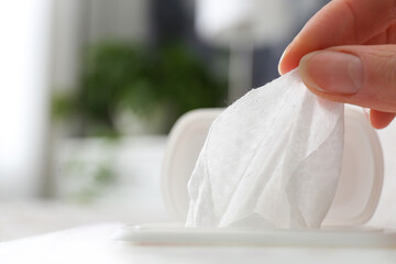 Wall Mural - Woman taking wet wipe from pack on blurred background, closeup