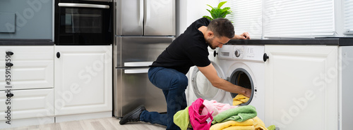 Fotografía Man Loading Clothes Into Washing Machine