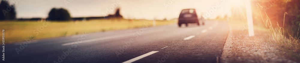 asphalt road view with a car in countryside at beautiful sunset - obrazy, fototapety, plakaty 