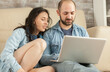 © DC Studio - Young couple looking at laptop while relaxing in living room.