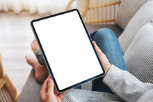 Mockup Image Of A Woman Holding Black Tablet Pc With Blank Desktop White Screen While Lying On A Sofa At Home