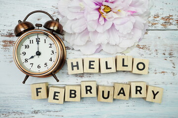 Hello February with alarm clock on wooden background