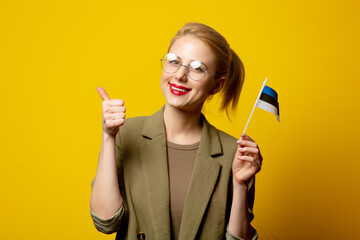 Wall Mural - Style blonde woman in jacket with Estonian flag on yellow background