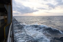 Barbed Wire Attached To The Ship Hull To Protect The Crew Against Piracy Attack In The Gulf Of Guinea In West Africa. On The Atlantic Ocean During Sunset, Windy Weather And Partly Clouded The Sky