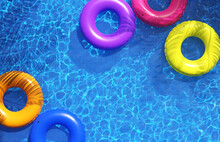  Multi-colored Swimming Rings In Swimming Pool. Pool Party, Summer Background. Top View