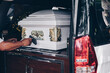 Close up of a casket loaded in a hearse or  funeral plan car or coach for the funeral procession. Selective focus. 