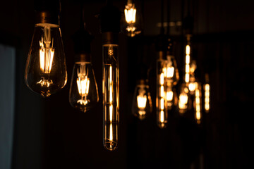 Set of vintage glowing light bulbs on dark background. Many different vintage light bulbs hanging from ceiling. close-up ampoule