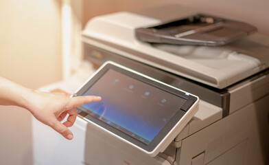 Female hand pressing the touchscreen monitor of the copy machine for copy a paper document,