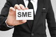 © banphote - Man hand holding paper card with word SME. Concept of small and medium-sized enterprises business.