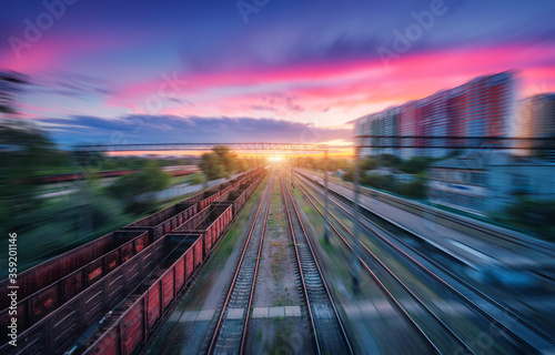 Fotomural Aerial view of railroad and colorful sky with clouds at sunset with motion blur effect in summer