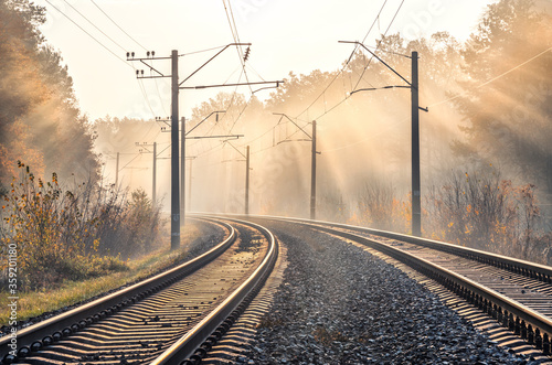 Fotografía Railroad in beautiful forest in fog at sunrise in autumn