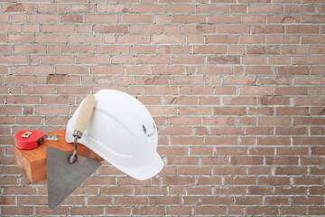 brick, white hard hat and Trowel, Red brick wall background. construction concept