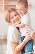 © zadorozhna - Son with mom hugging in kitchen. Happy family.