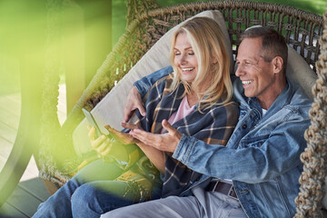 Wall Mural - Cheerful couple relaxing with smartphone in open air