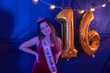 © Mat Hayward - Pretty teenage girl with big smile at her sweet sixteen birthday party. Decorations include gold mylar balloons in the shape of 16.