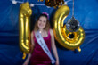 © Mat Hayward - Pretty teenage girl with big smile at her sweet sixteen birthday party. Decorations include gold mylar balloons in the shape of 16.