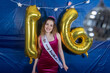 © Mat Hayward - Sixteen year old girl wearing a tiara and sash celebrates her birthday with a party featuring gold 16 balloons