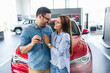 Beautiful young smiling couple holding a key of their new car.