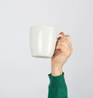 © nndanko - white ceramic cup in a female hand on a white background