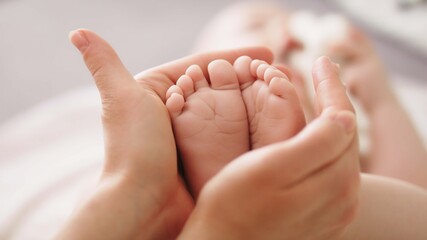 mother massaging and tickling small baby feet. close up slow motion shot.