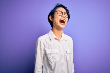 Sticker - Young beautiful asian girl wearing casual shirt and glasses standing over purple background angry and mad screaming frustrated and furious, shouting with anger. Rage and aggressive concept.