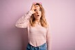 © Krakenimages.com - Young beautiful blonde woman wearing casual sweater and sunglasses over pink background doing ok gesture shocked with surprised face, eye looking through fingers. Unbelieving expression.