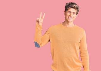 Young handsome man wearing casual clothes showing and pointing up with fingers number two while smiling confident and happy.