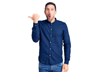 Young handsome man wearing casual shirt surprised pointing with hand finger to the side, open mouth amazed expression.