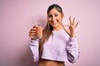 © Krakenimages.com - Young beautiful fitness woman drinking protein chocolate milkshake before gym doing ok sign with fingers, excellent symbol