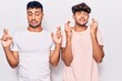 © Krakenimages.com - Young gay couple wearing casual clothes gesturing finger crossed smiling with hope and eyes closed. luck and superstitious concept.