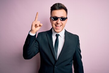 Wall Mural - Young handsome caucasian business man wearing funny thug life glasses pointing finger up with successful idea. Exited and happy. Number one.