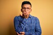 © Krakenimages.com - Young handsome latin man wearing casual shirt and glasses over yellow background looking at the camera blowing a kiss with hand on air being lovely and sexy. Love expression.