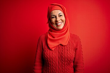 Canvas Print - Middle age woman wearing traditional muslim hijab standing over isolated red background with a happy and cool smile on face. Lucky person.