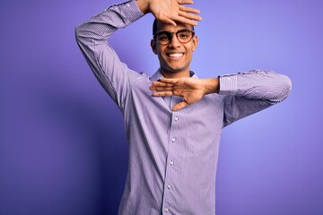 Wall Mural - Handsome african american man wearing striped shirt and glasses over purple background Smiling cheerful playing peek a boo with hands showing face. Surprised and exited