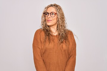 Wall Mural - Young beautiful blonde woman wearing casual sweater and glasses over white background smiling looking to the side and staring away thinking.