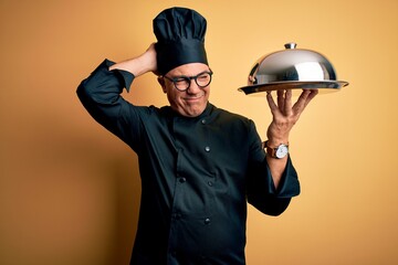 Sticker - Middle age handsome grey-haired waiter man wearing cooker uniform and hat holding tray confuse and wondering about question. Uncertain with doubt, thinking with hand on head. Pensive concept.