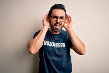 Sticker - Handsome man with beard wearing t-shirt with volunteer message over white background Trying to hear both hands on ear gesture, curious for gossip. Hearing problem, deaf